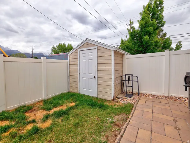 Outdoor storage shed with light-colored siding and a panel door
