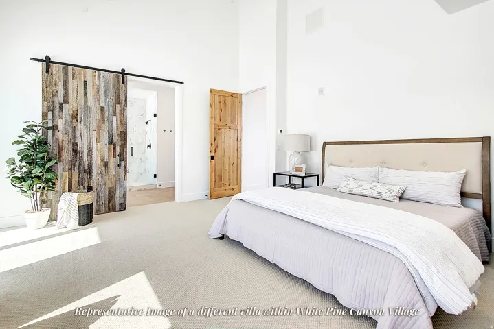 Vaulted ceiling bedroom with light-toned carpeting and white walls
