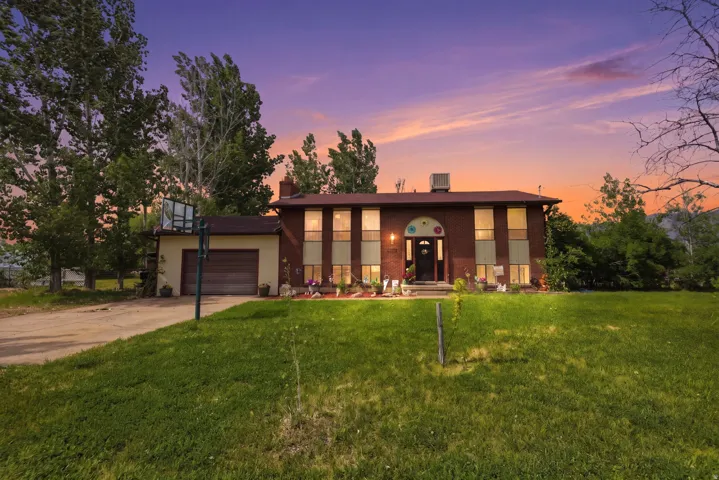 Two-story brick residence featuring an attached garage with a sectional door, a central arched entry, and a prominent chimney