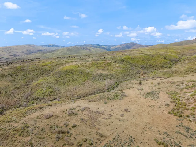 Expansive open land featuring rolling hills and natural vegetation