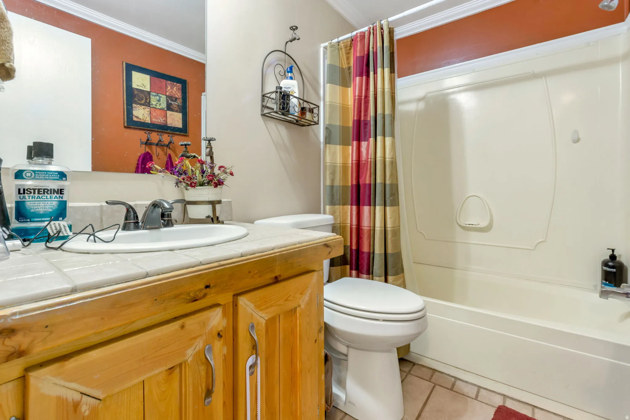 Bathroom featuring a tile-top vanity with wood cabinetry, a built-in sink, and a two-handle faucet