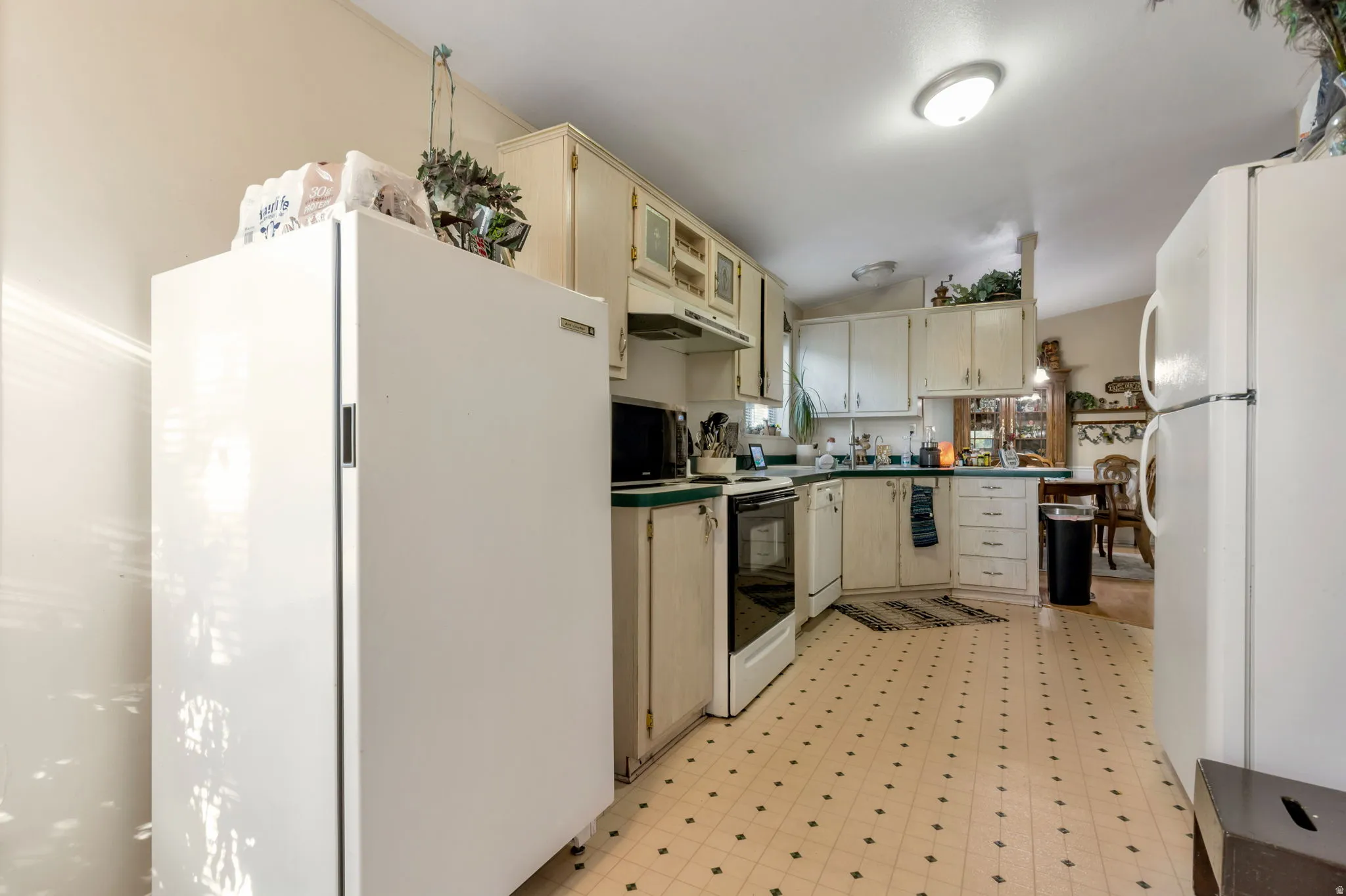 Kitchen featuring off-white cabinetry with decorative glass inserts, a white electric range, and a white dishwasher