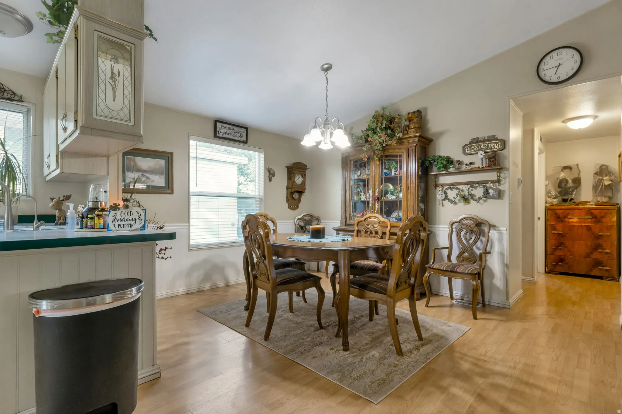 Dining area featuring wood-finish flooring, two large windows with blinds, and wainscoting