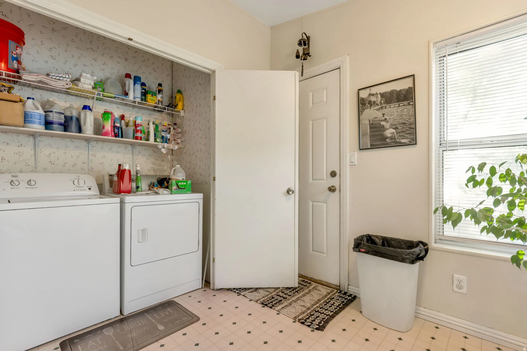 Dedicated laundry area featuring a washer and dryer, open shelving, a window with horizontal blinds, and a paneled door