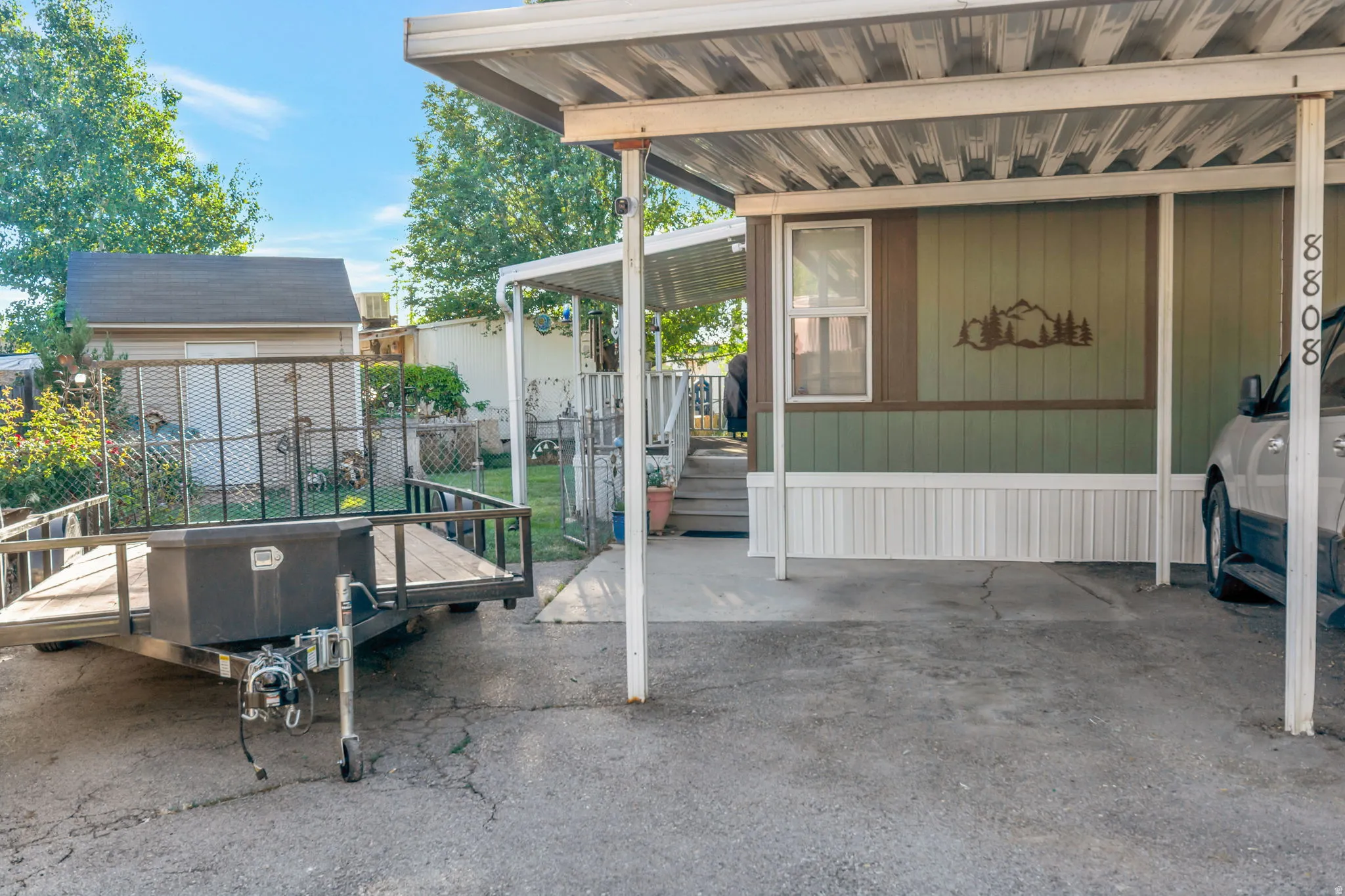 Carport parking offering shade and protection, featuring a light green and brown exterior with decorative mountain motif