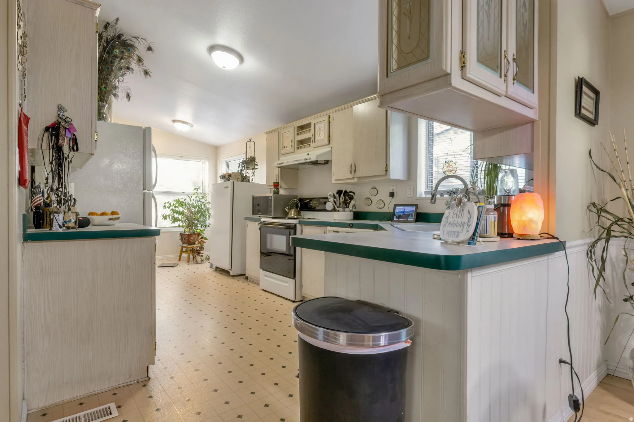 Kitchen featuring white cabinetry, a green countertop, white appliances, and patterned flooring