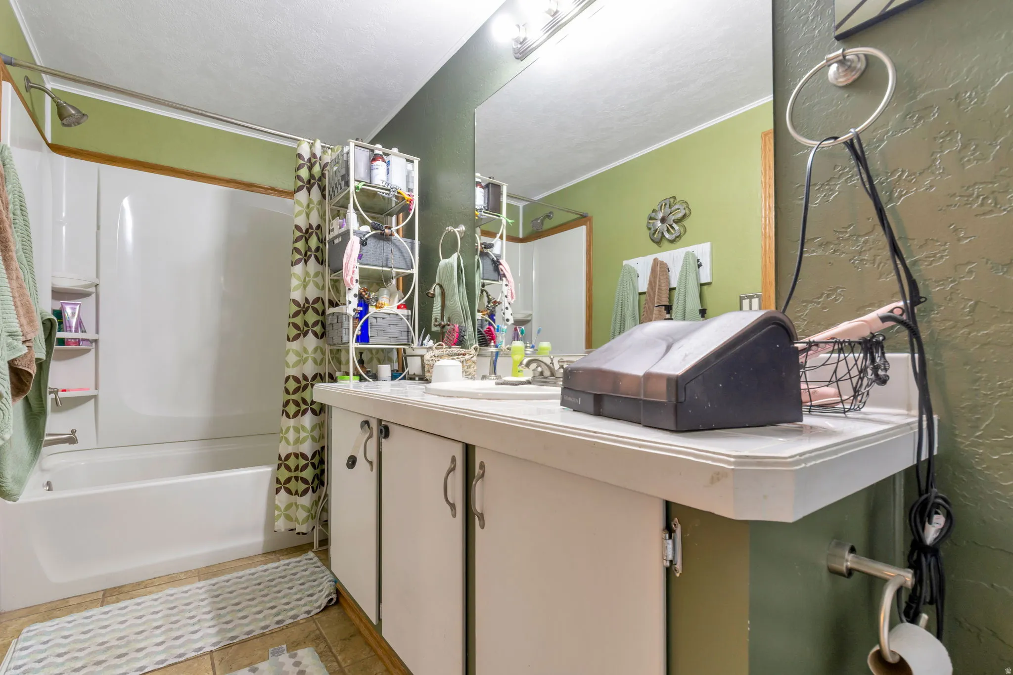 Bathroom featuring a single vanity with a laminate countertop, integrated sink, and white cabinetry