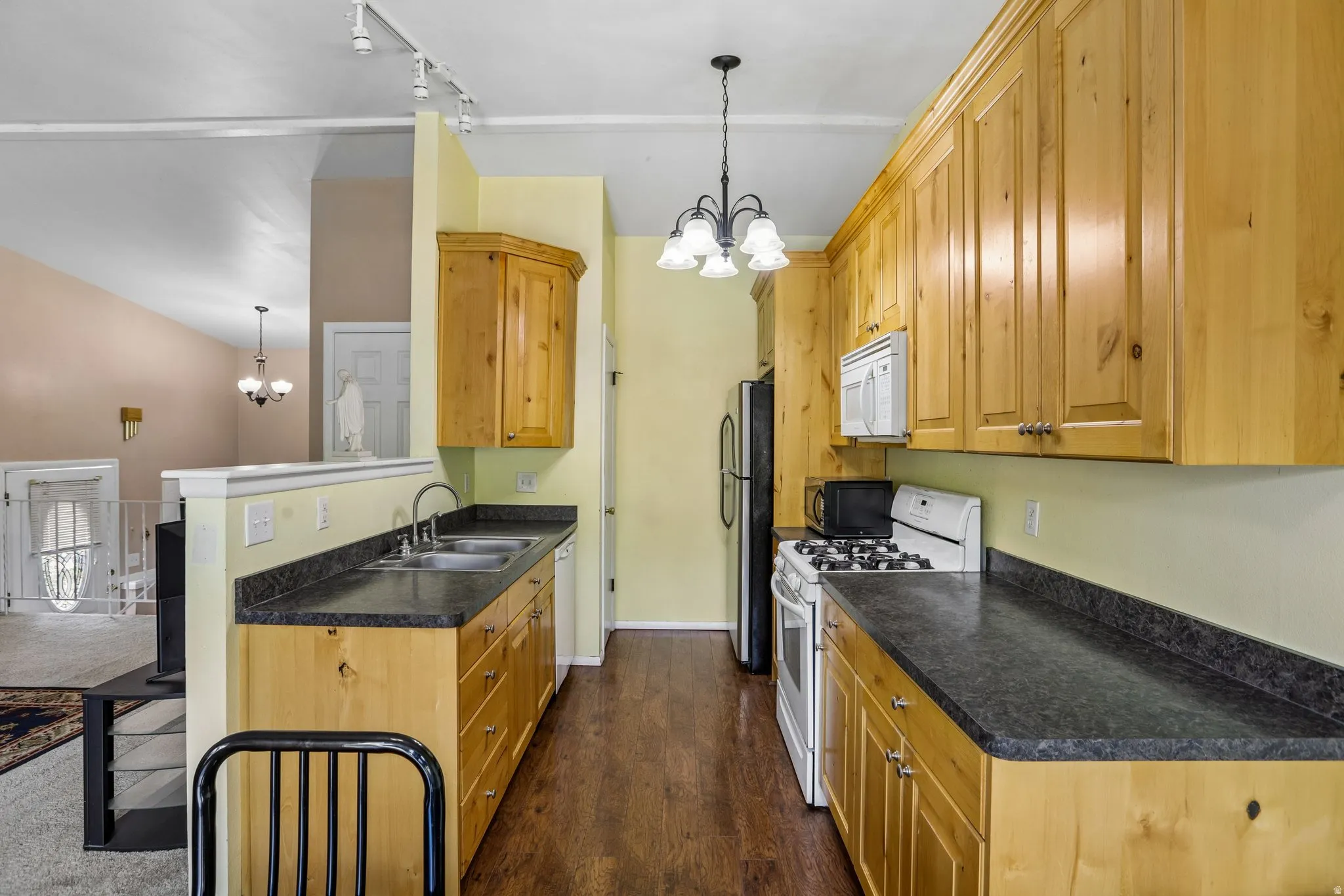 Galley kitchen featuring wood-finish cabinetry, dark countertops, and stainless steel sink