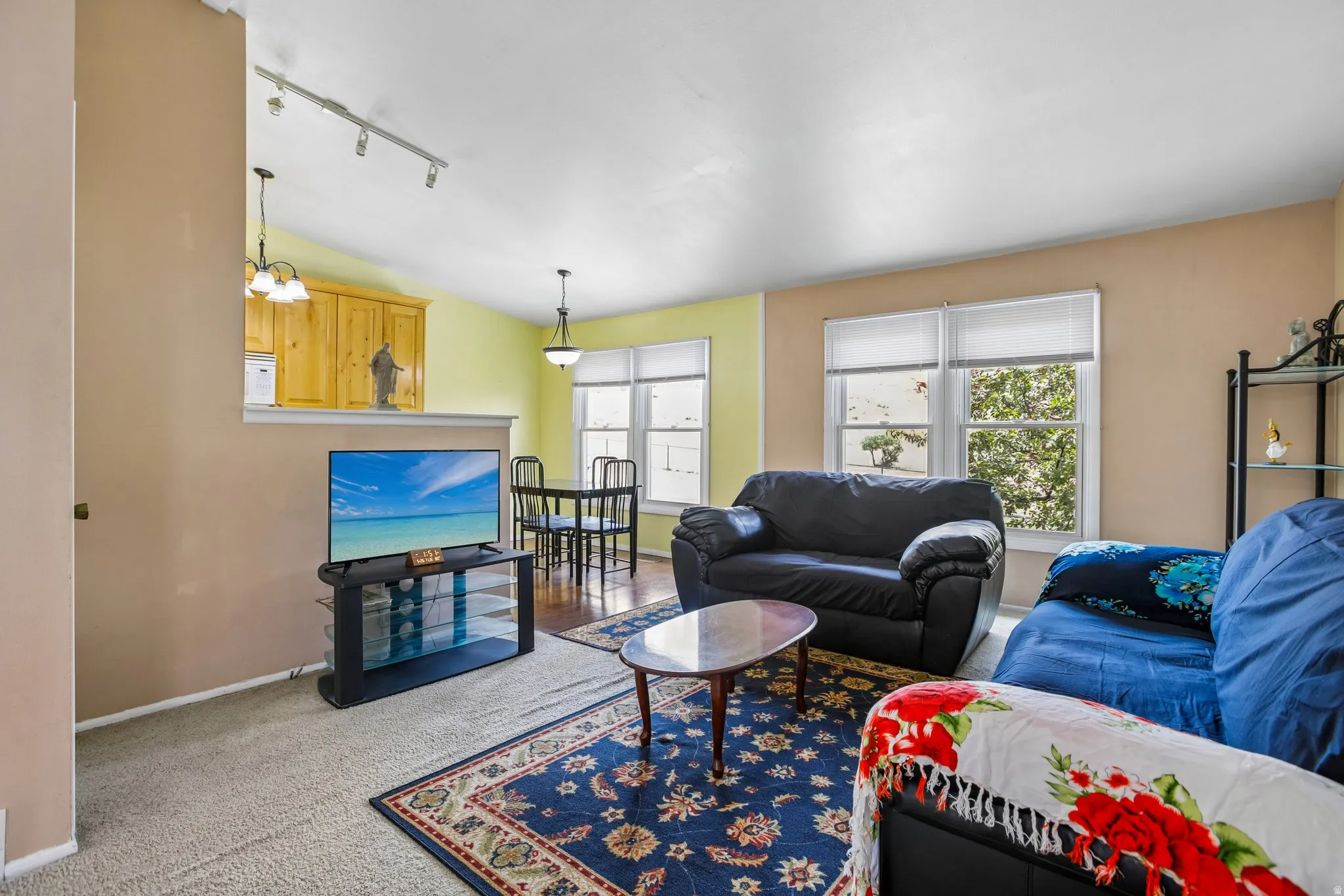 Living area featuring light beige carpeting, two windows with blinds, and recessed lighting
