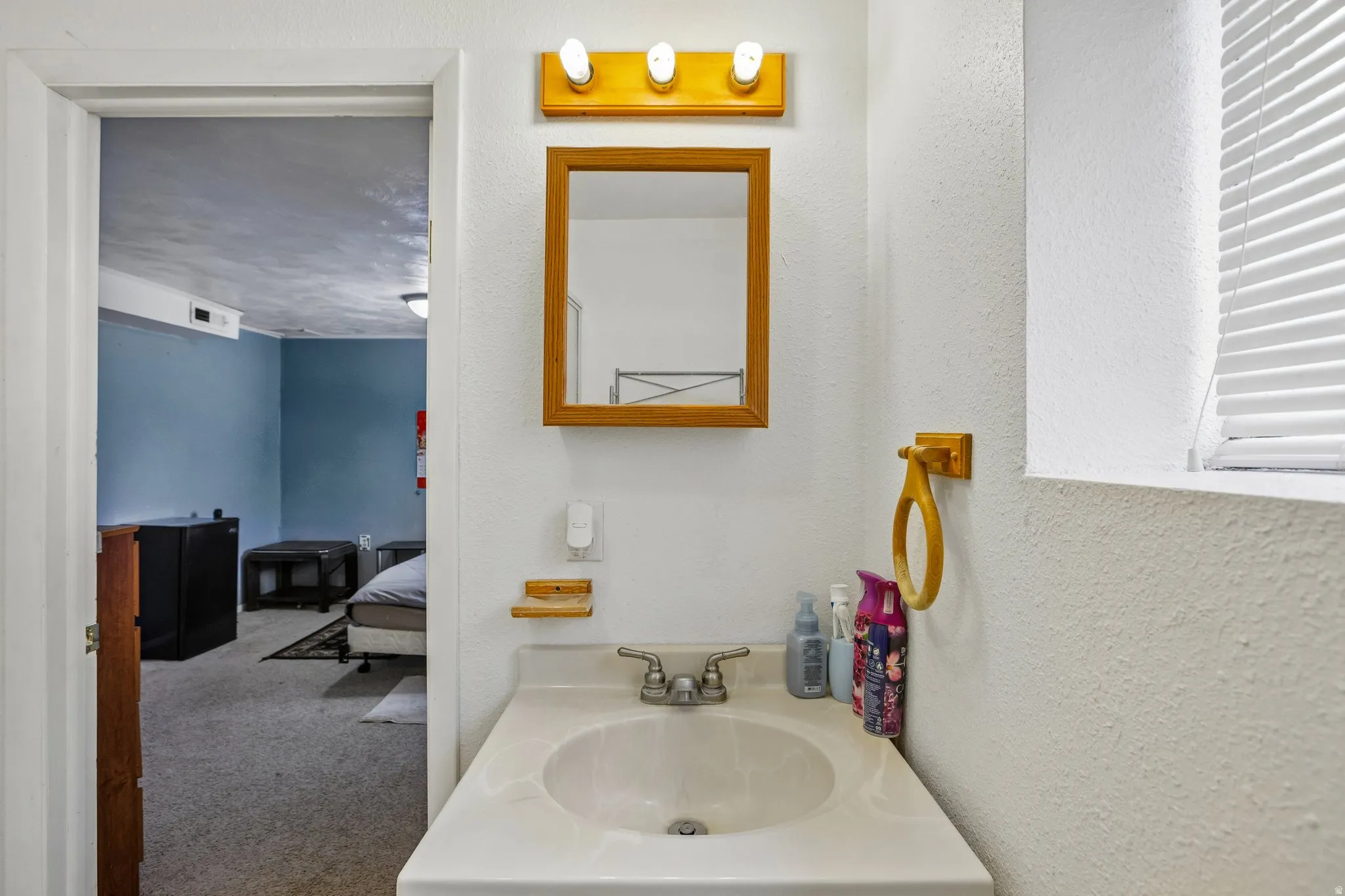 Bathroom vanity featuring a single basin sink, a wall-mounted mirror with a wooden frame, and overhead lighting