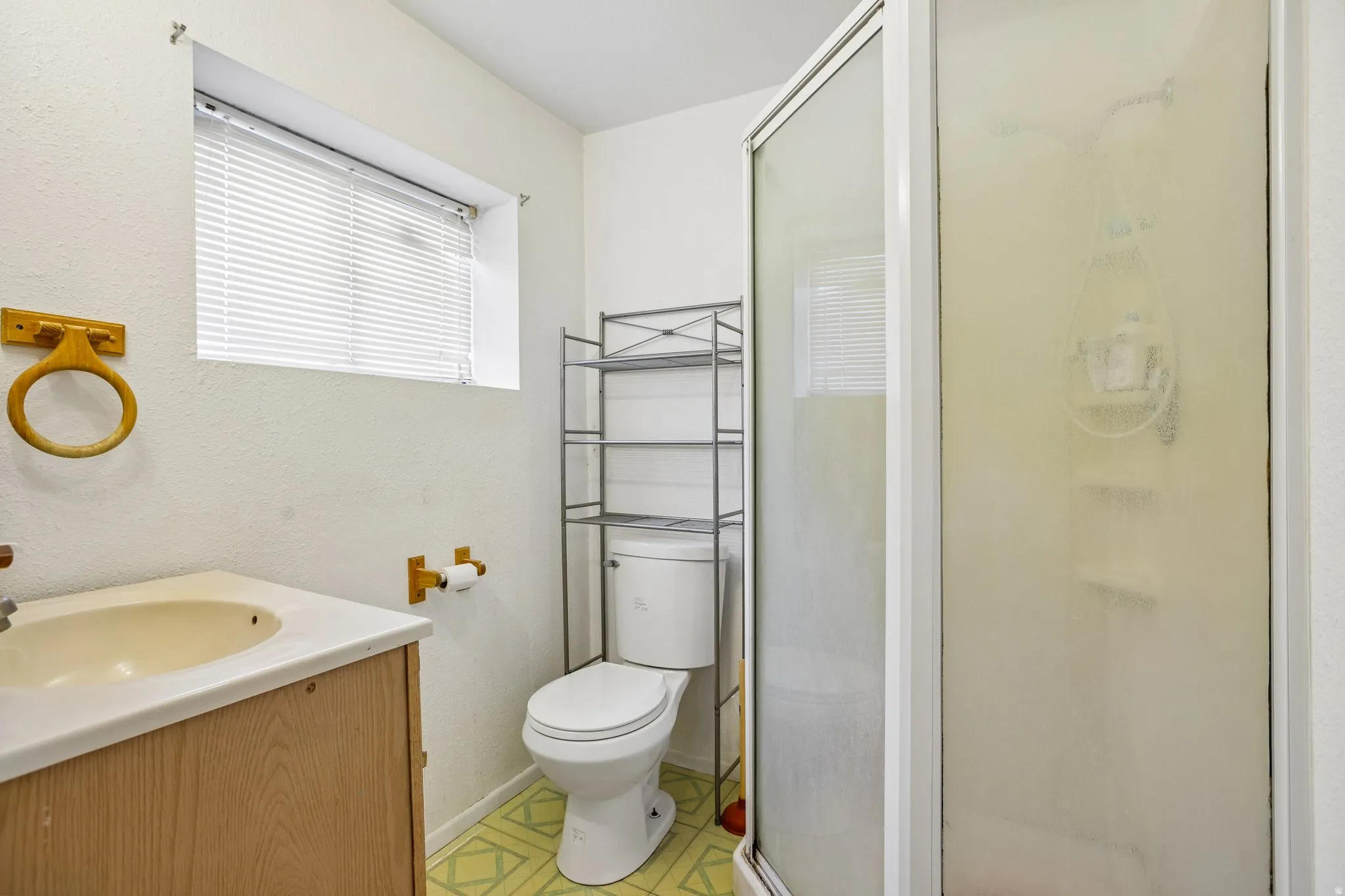 Three-piece bathroom featuring a shower stall with a frosted glass enclosure, a toilet, and a vanity with an integrated sink