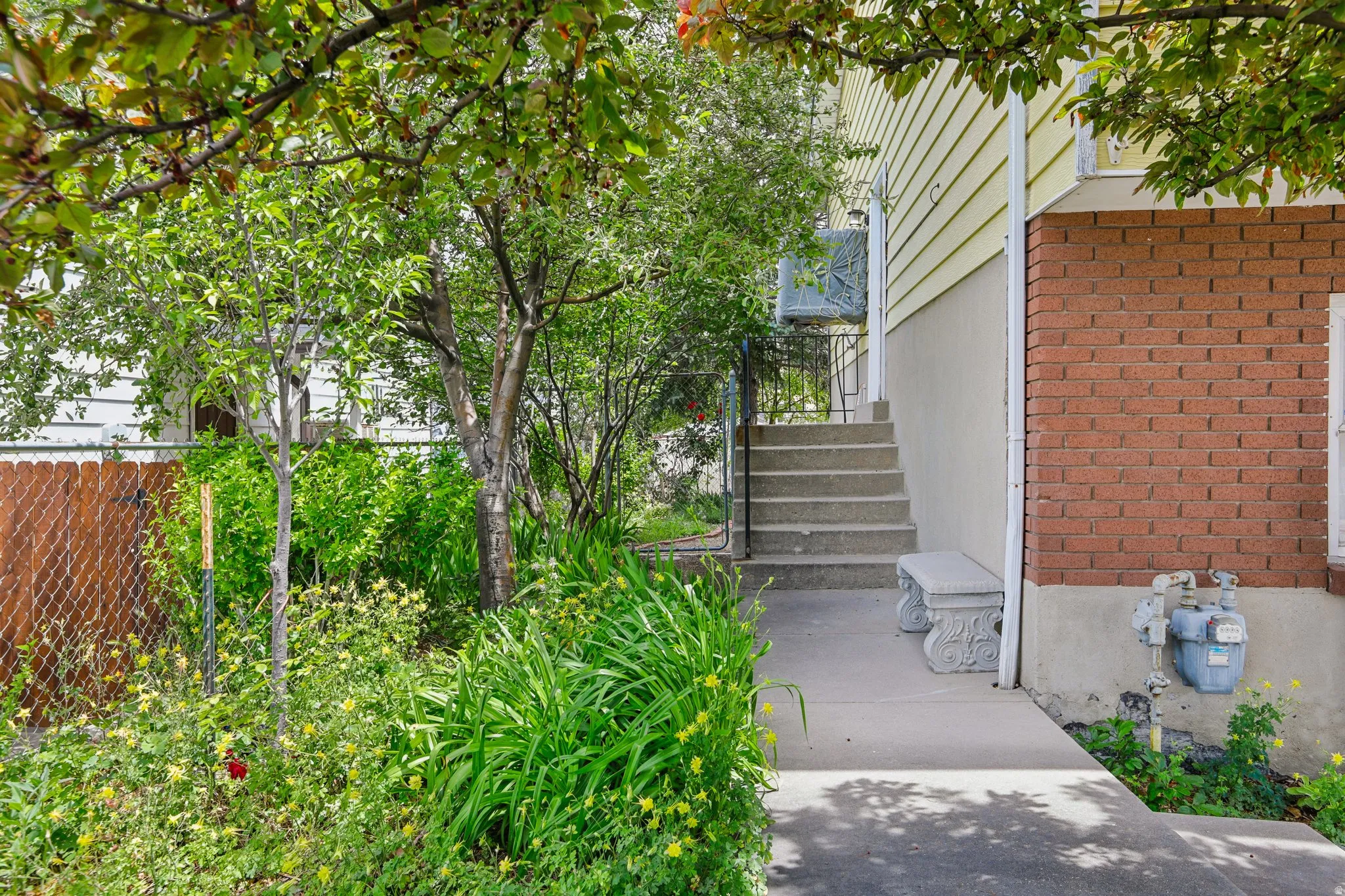 Exterior featuring concrete stairs with metal handrail, brick and siding facade, and a mature tree