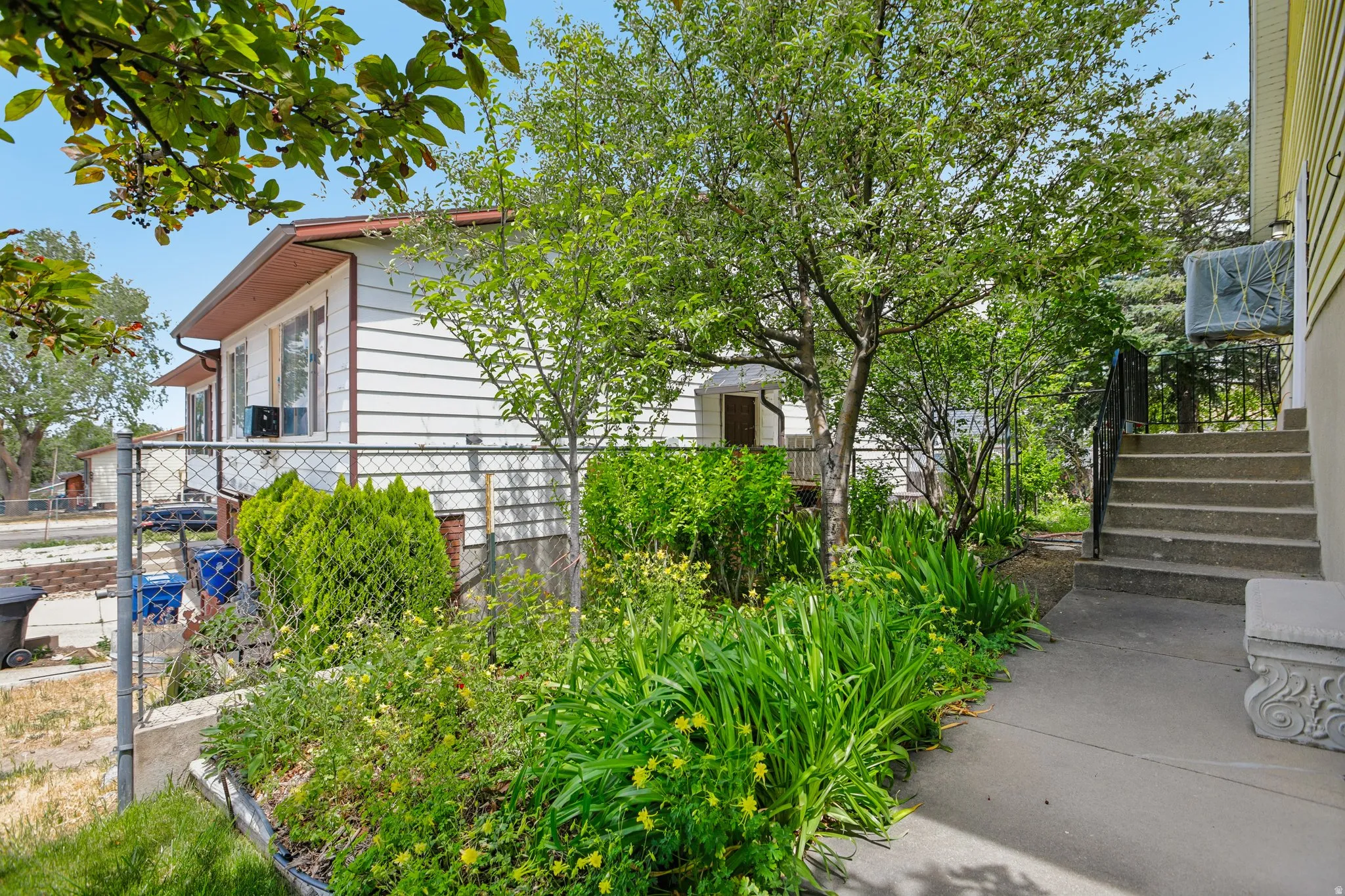 Exterior walkway leading to concrete steps with a black metal railing