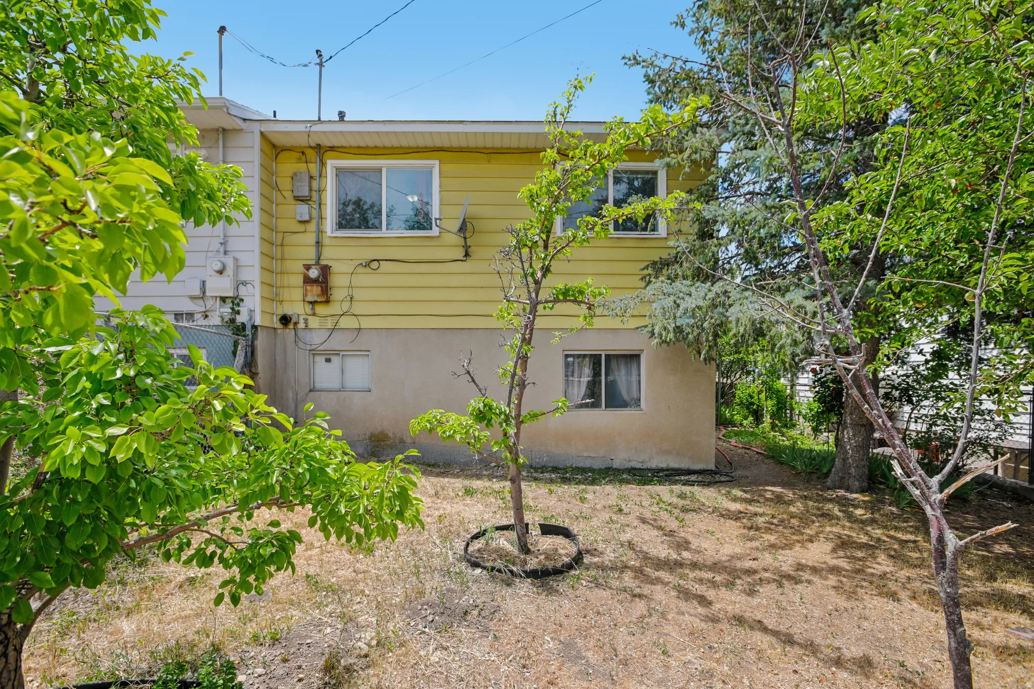Yellow siding exterior with white window trim and a concrete foundation