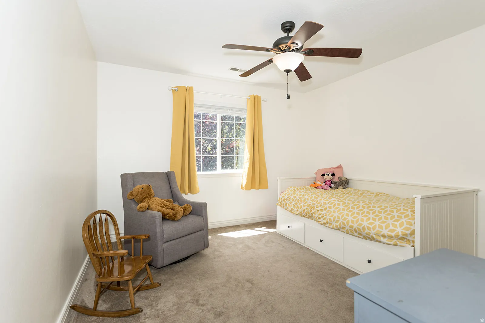 Carpeted room featuring a ceiling fan with integrated lighting, a window with exterior scenery, and white wall finishes