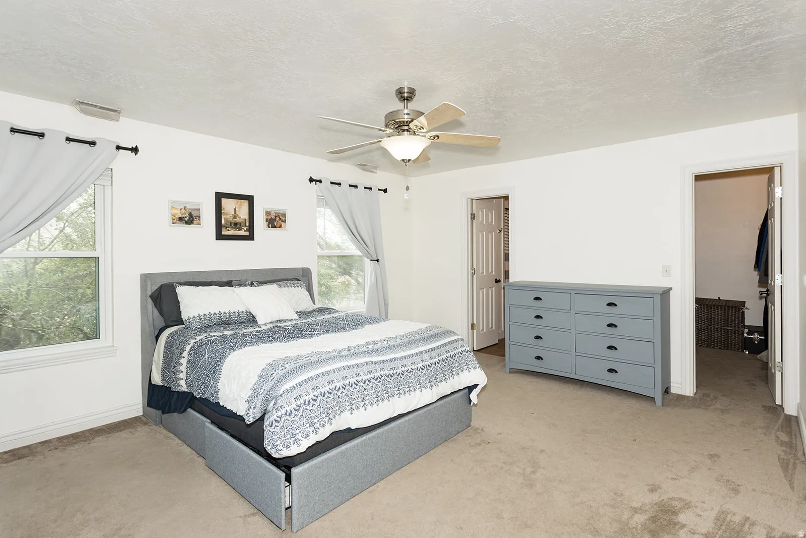 Carpeted room featuring a ceiling fan with integrated lighting, two windows, and a doorway leading to a closet space