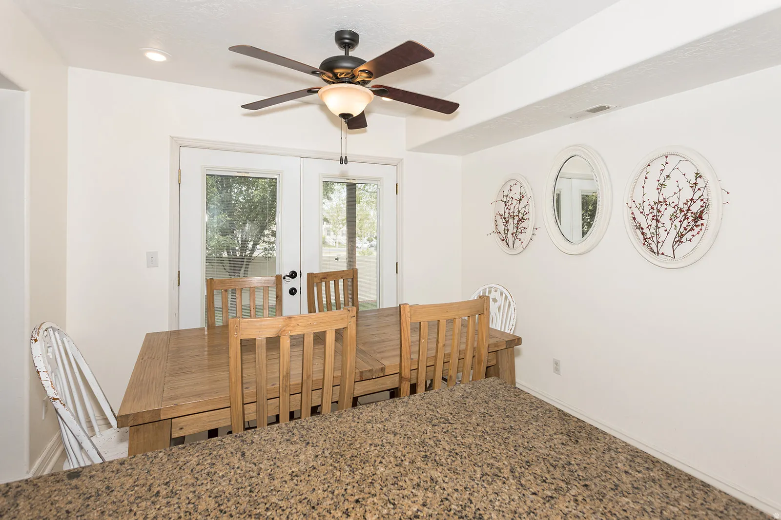 Dining area featuring double French doors, a ceiling fan with integrated lighting, recessed ceiling lighting, and a textured countertop peninsula