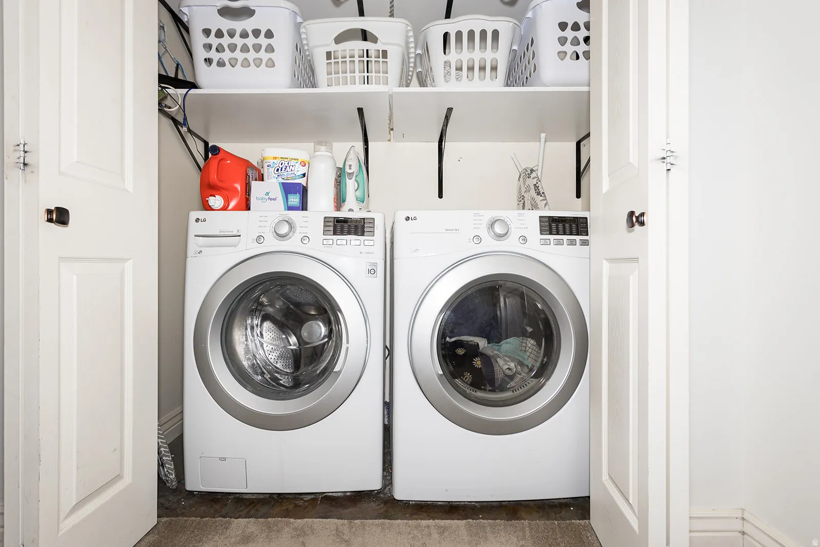 Dedicated laundry closet featuring a stackable washer and dryer, white shelving, and bi-fold doors