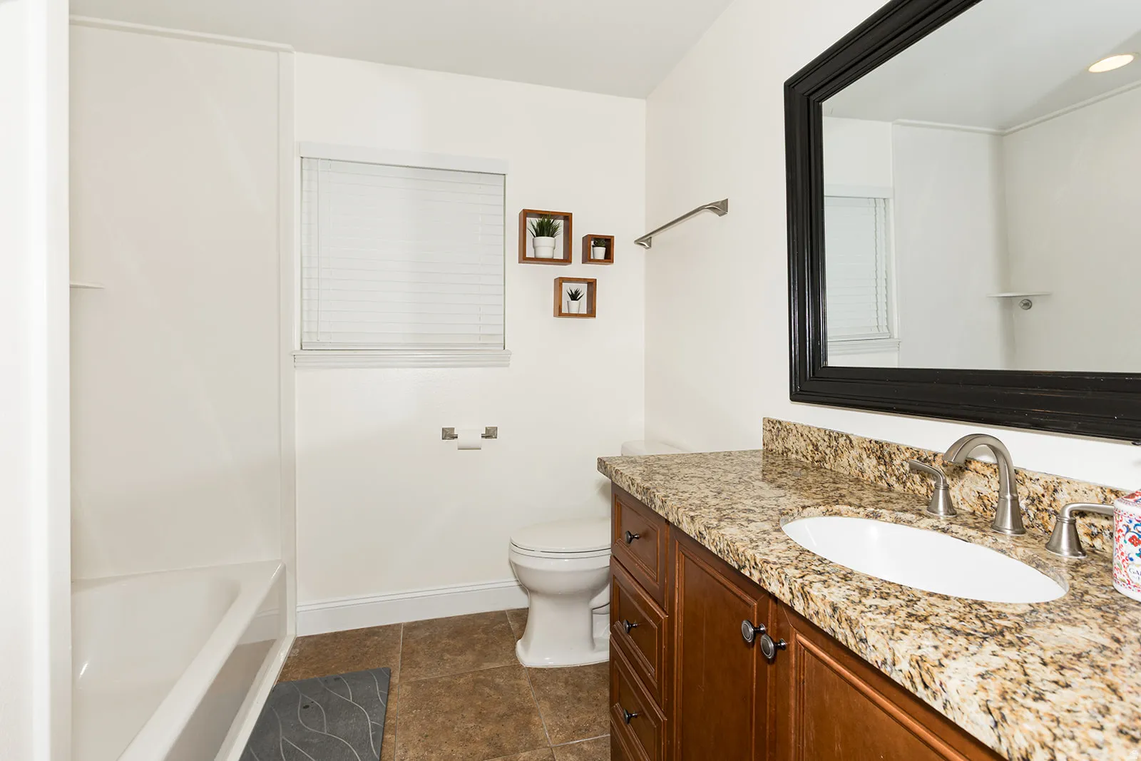 Bathroom vanity with stone countertop, undermount sink, and wood-finish cabinetry