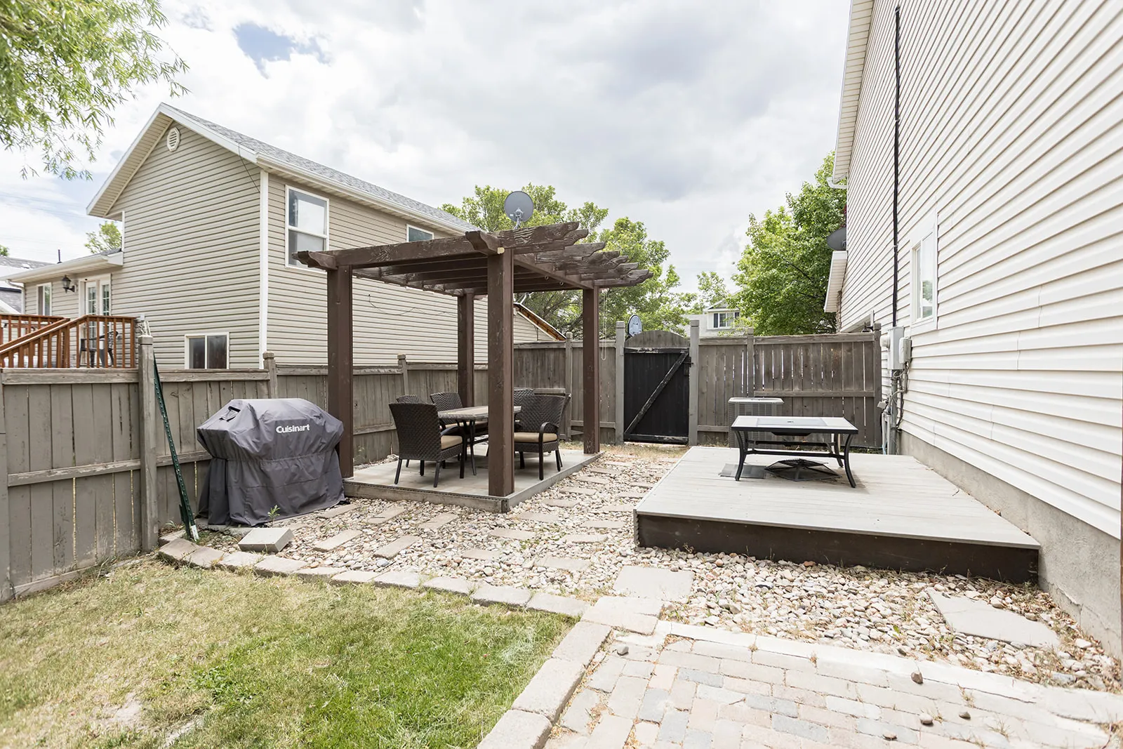 Private backyard oasis featuring a pergola-covered patio, an elevated deck, and a fenced perimeter