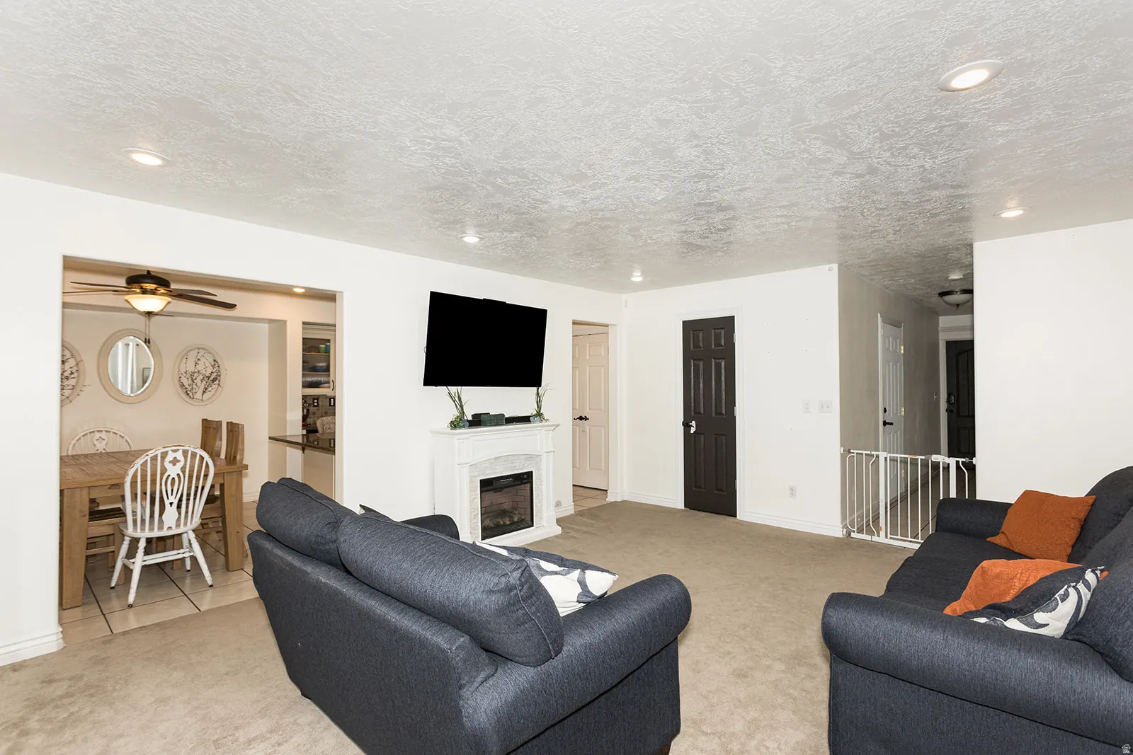 Carpeted living area featuring a built-in fireplace with a white surround and an overhead television mount