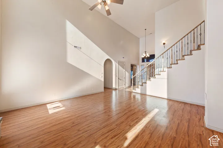 Soaring vaulted ceilings, wood-finish flooring, and a staircase featuring wrought iron balusters