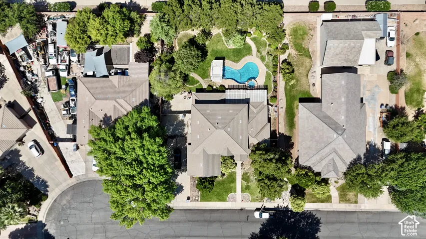 Aerial perspective showcasing a property with a distinct roofline, a large backyard featuring a swimming pool, and established landscaping