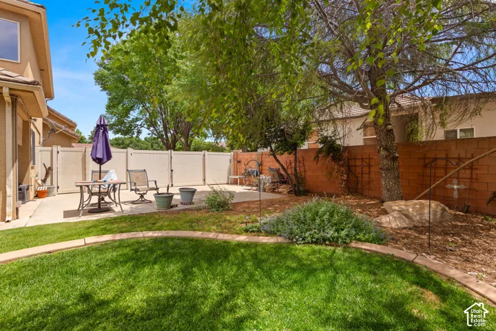 Expansive backyard featuring a concrete patio, a manicured lawn area, and a privacy fence