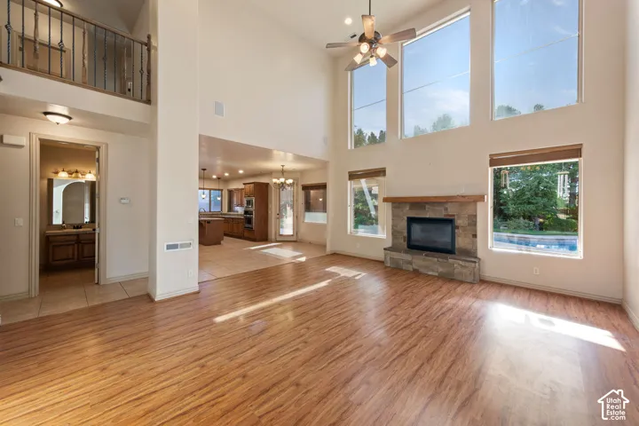 Vaulted ceilings, wood-finish flooring, stone-clad fireplace with wood mantle, ceiling fan, and extensive fenestration