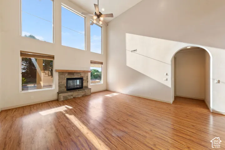 Vaulted ceiling living space featuring wood-finish flooring, a stone-faced fireplace with a wood mantle, and an arched wall niche