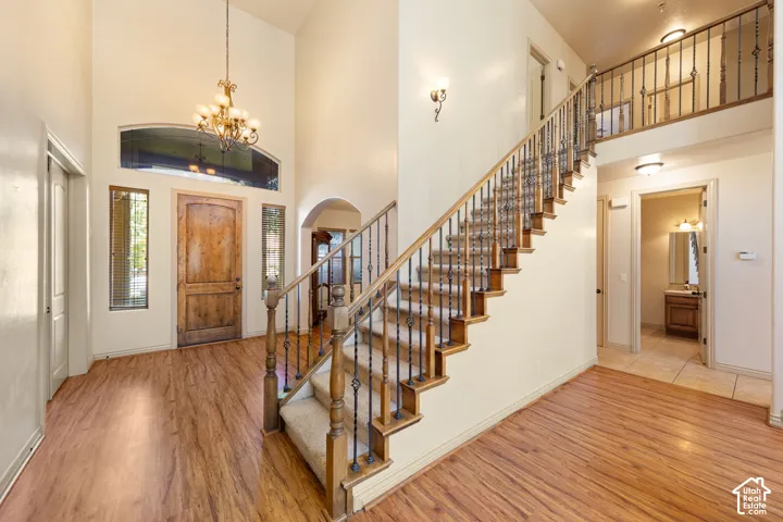 Grand foyer featuring a vaulted ceiling with an ornate chandelier, a rustic wood-plank entry door, and wood-finish flooring