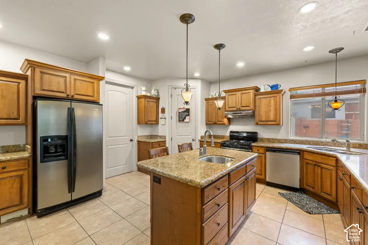 Kitchen featuring a central island with an undermount sink, granite countertops, and wood cabinetry