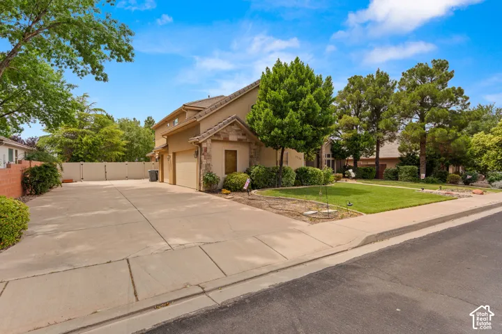 Exterior with stucco finish and stone accents, featuring a two-car garage and a long concrete driveway