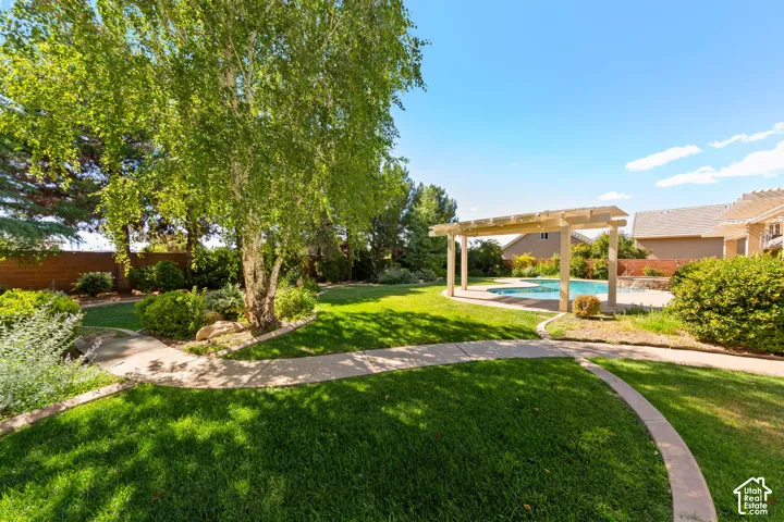 Expansive green lawn with a mature deciduous tree, bordered by curving concrete pathways and established shrubs