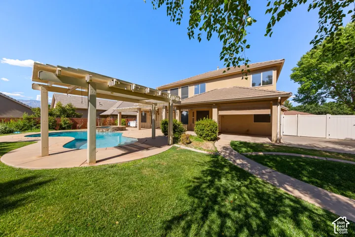 Lush green lawn with a freeform swimming pool, extensive patio space, and a wood pergola