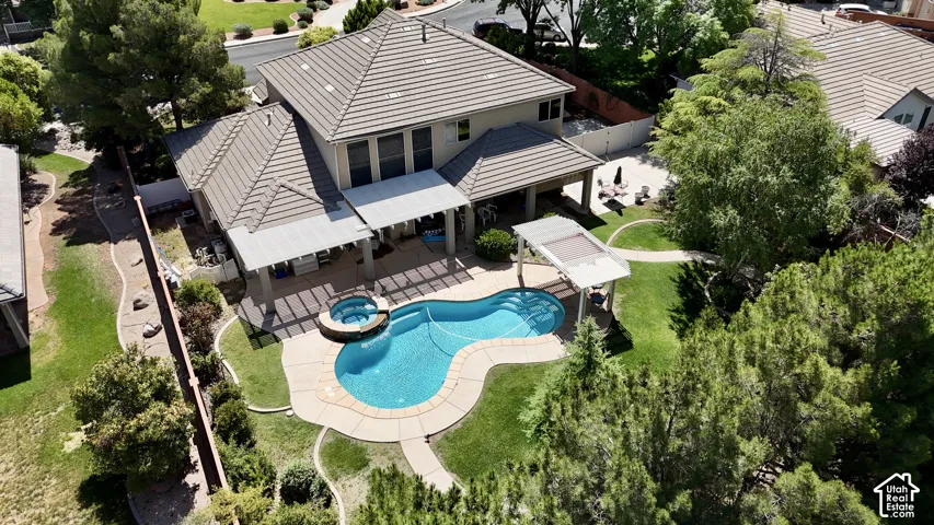 Expansive backyard featuring a freeform swimming pool with integrated spa, concrete coping, and a surrounding lawn