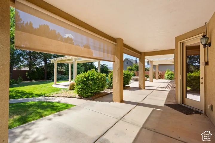 Expansive covered patio featuring concrete flooring, roll-down shade screens, and direct yard access