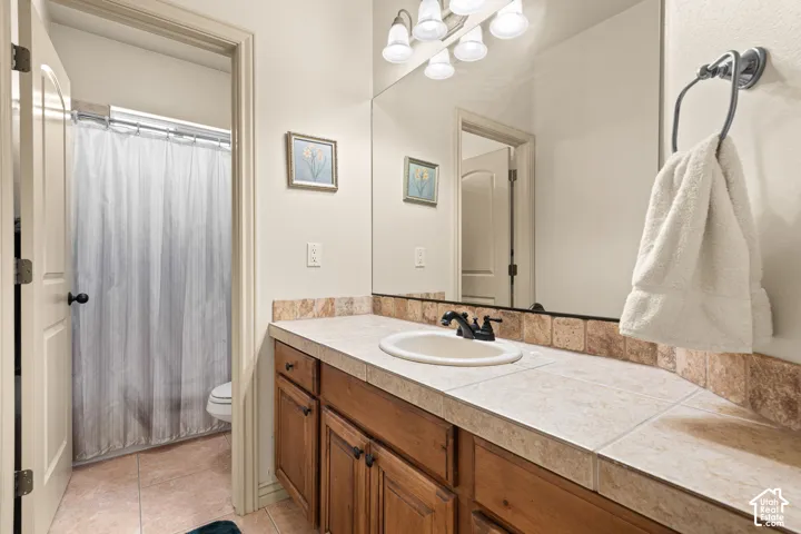 Bathroom vanity with tile countertop, integrated sink, and wood-finish cabinetry