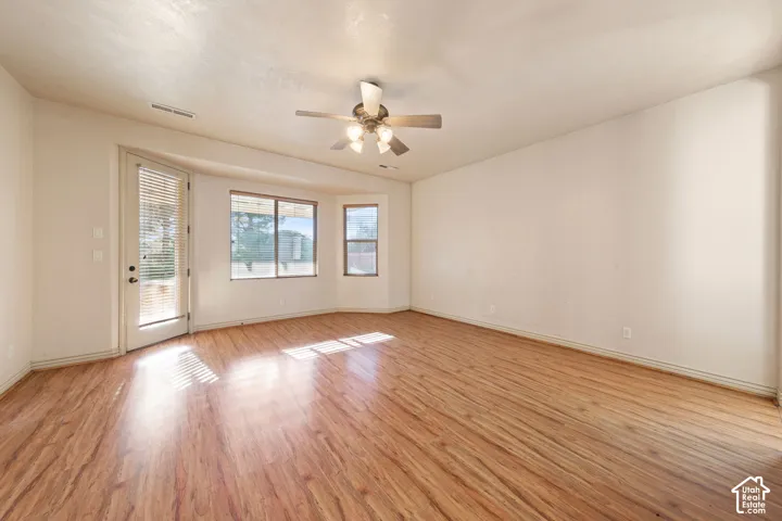 Wood-finish flooring, ceiling fan, multiple windows, and a glass-paneled door