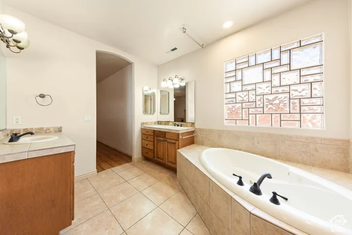 Soaking tub with a tiled surround, complemented by a decorative glass block window