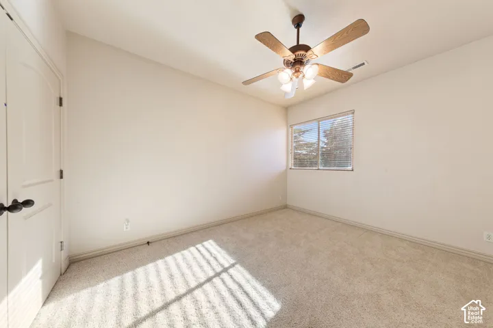 Neutral wall finishes, carpeted flooring, a window with blinds, and a ceiling fan with integrated lighting