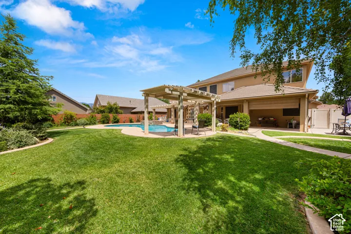 Expansive backyard featuring a large swimming pool, a wooden pergola, and a spacious lawn