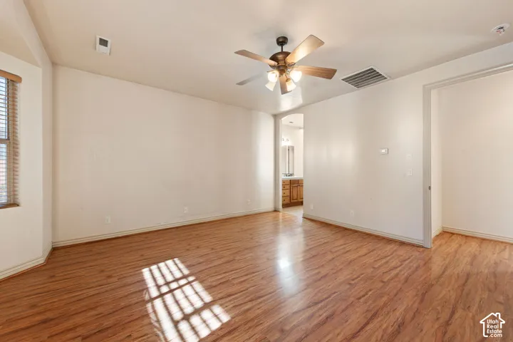 Wood-finish flooring, ceiling fan with integrated lighting, window with blinds, and neutral wall tones