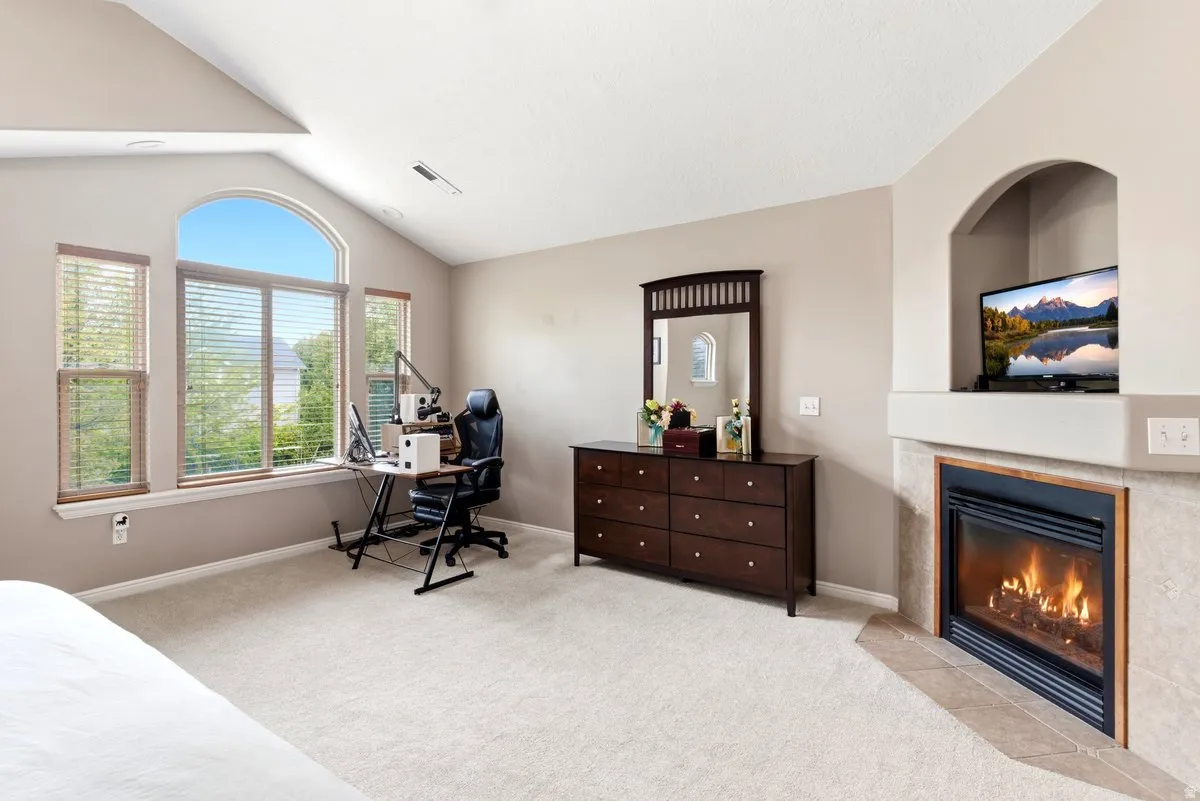 Vaulted ceiling room featuring an arched window, three additional windows, a built-in fireplace with a tile surround, and an integrated media niche