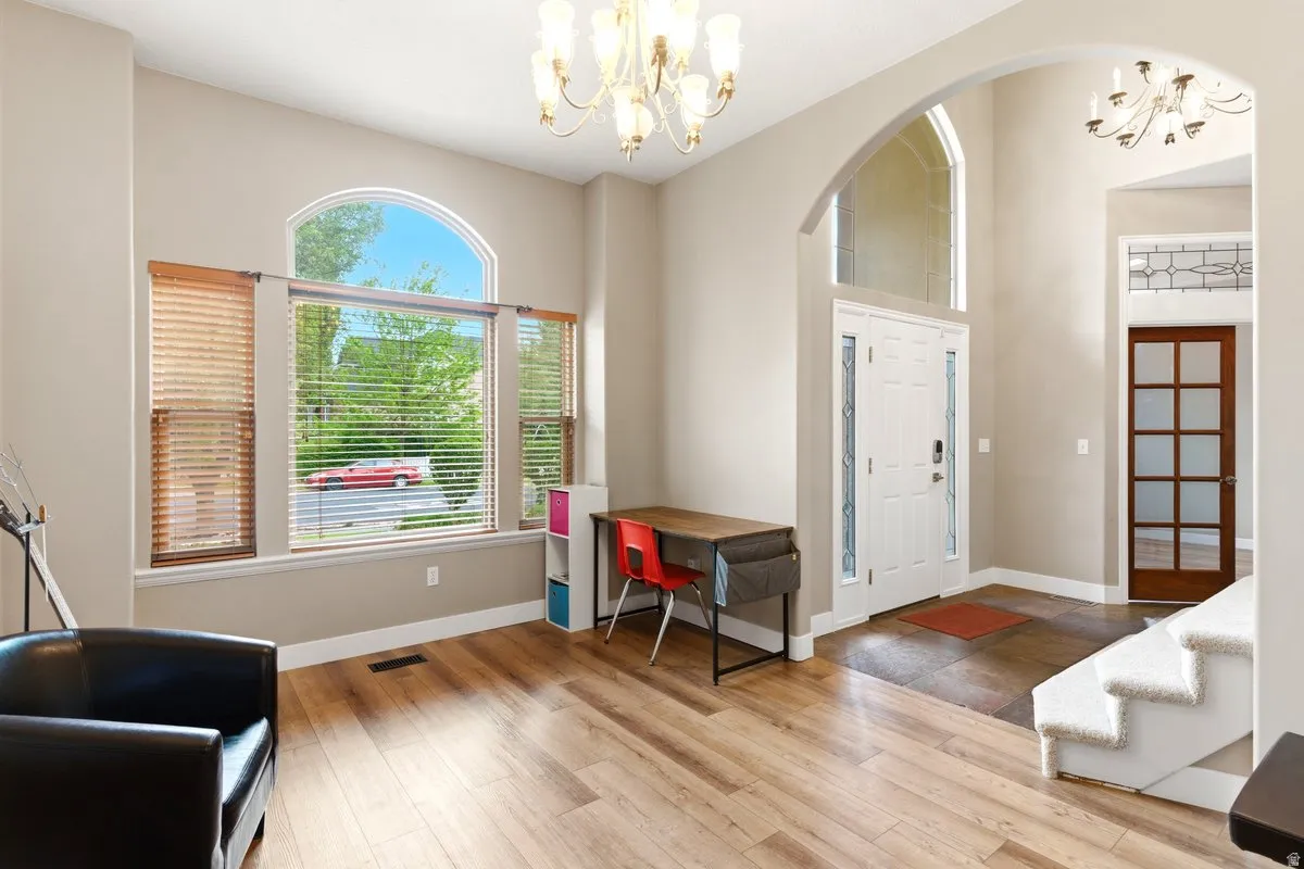 Entryway featuring a white paneled front door with decorative glass side panels and a transom window, a grand arched opening, and a chandelier
