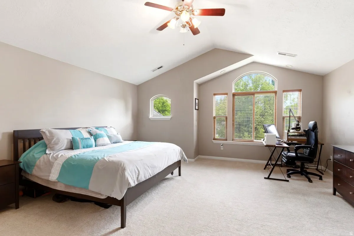 Spacious room featuring vaulted ceilings, a large arched window with two flanking windows, a round-top window, and light-toned carpeting