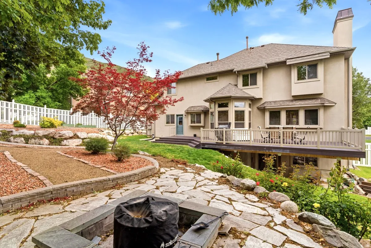 Rear exterior featuring a large elevated deck, stucco siding, and multiple bay windows