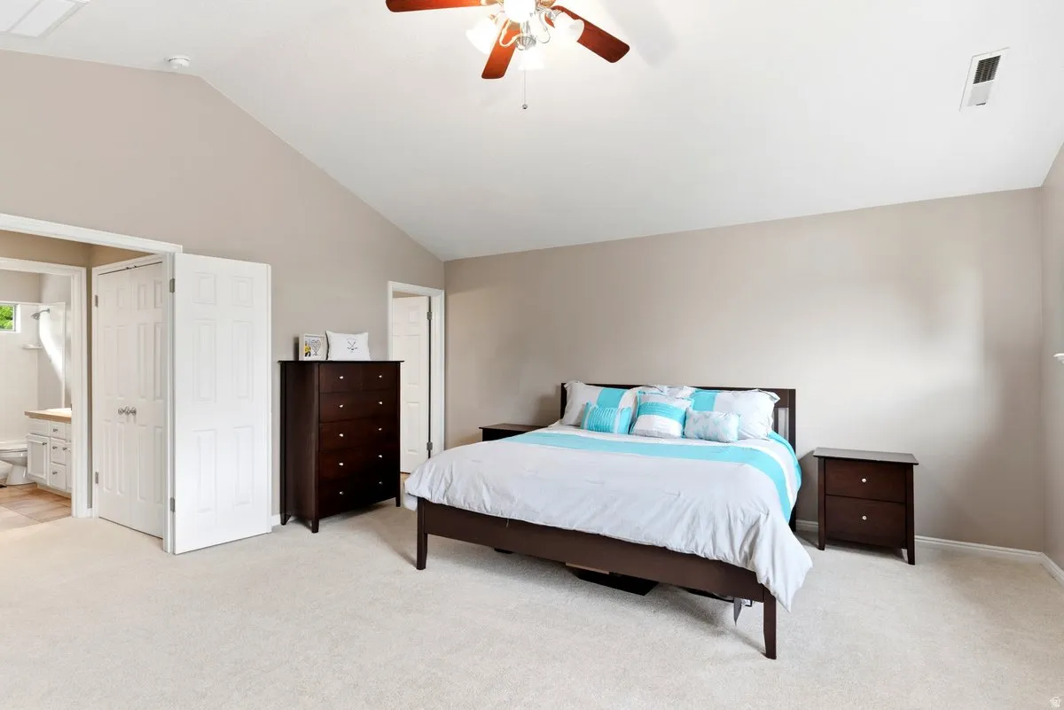 Spacious room featuring vaulted ceilings, light-colored carpeting, and a ceiling fan with integrated lighting