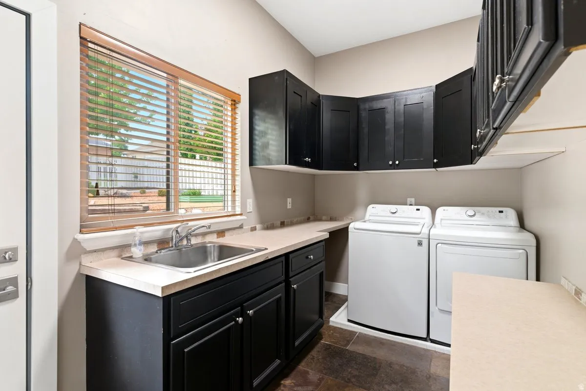 Laundry area featuring dark cabinetry, a utility sink, and a spacious countertop