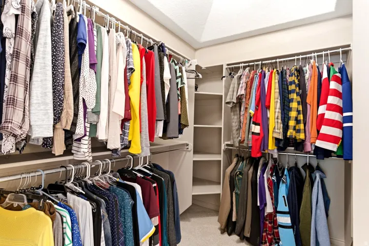 Walk-in closet featuring multiple hanging rods, built-in shelving, and neutral carpeting